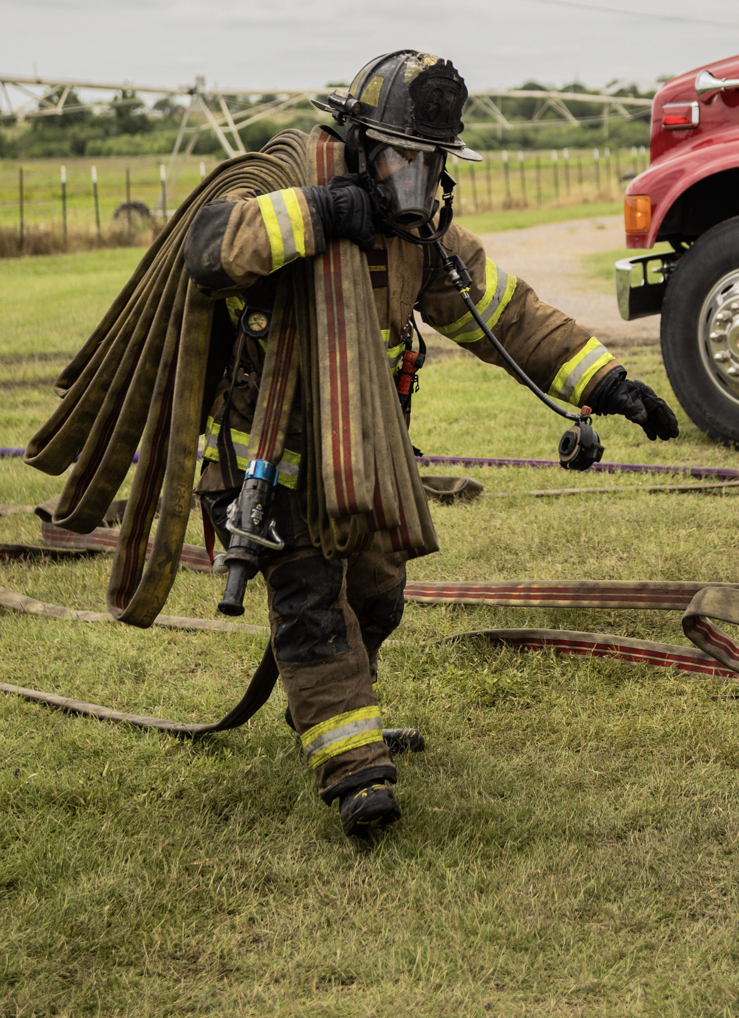 firefighter in gear walking with hose bundled on his shoulder
